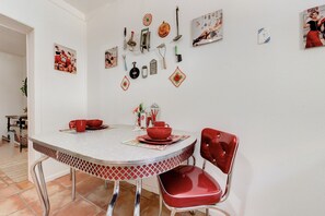 A dining area with a round table, red chairs, and various kitchen utensils and decorations on the wall. - The Bung – A Little Slice of Paradise! (Lubbock)