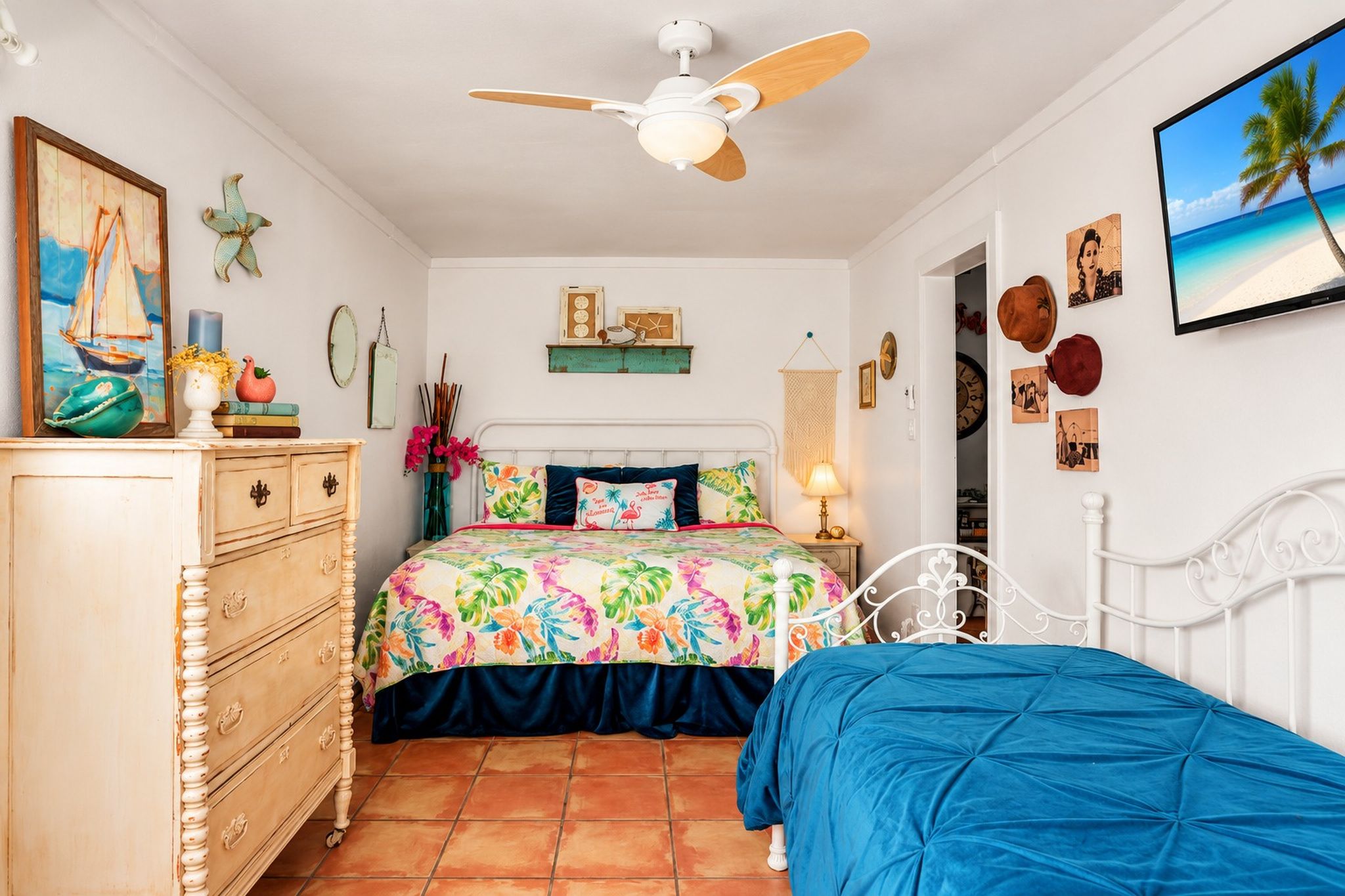 Ein Schlafzimmer mit Bett, Kommode, Deckenventilator und verschiedenen Wanddekorationen.