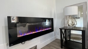 Seinälle asennettu litteä näyttötelevisio, moderni lamppu sivupöydällä ja puulattia.