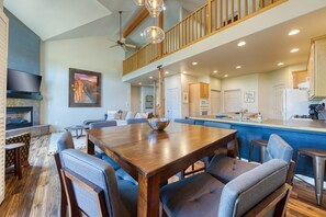 A spacious living area with a large wooden dining table, comfortable seating, a fireplace, and a kitchen area with modern appliances.
