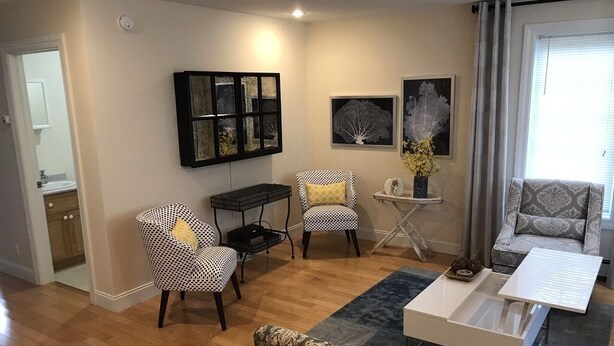Ein Wohnzimmer mit einer Couch, zwei gemusterten Sesseln, einem Couchtisch und Kunstwerken an den Wänden.