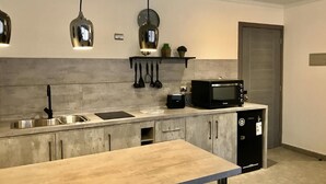 Eine moderne Küche mit einem Holztisch, einer Spüle, einer Mikrowelle und hängenden Küchenutensilien.