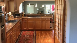 A kitchen with wooden cabinets, a granite countertop, a built-in oven, and a central island with a sink. - Harmony House - a serene place to relax and renew (Sebastopol)
