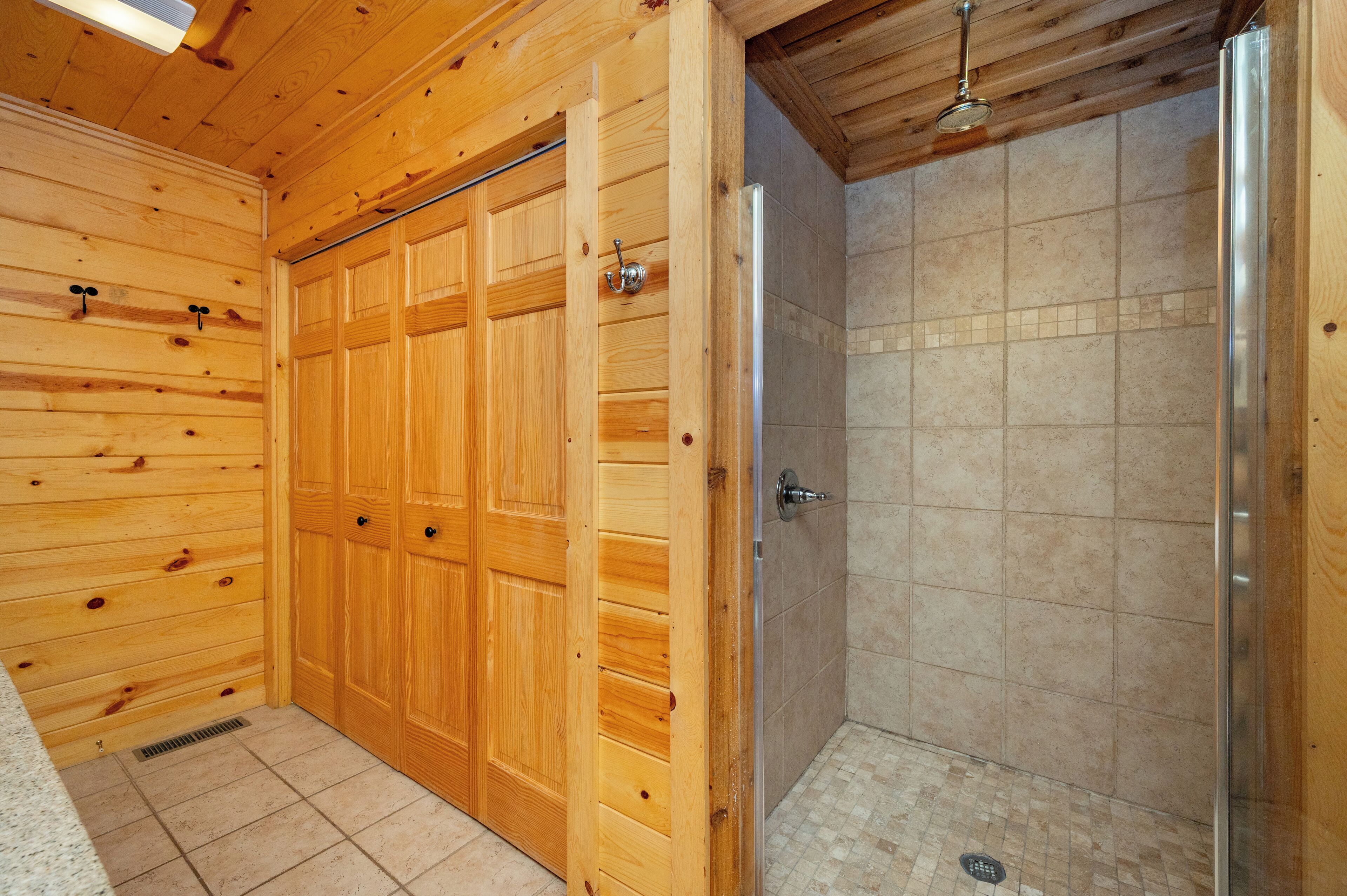 A wooden interior with a shower area and a door with a handle.