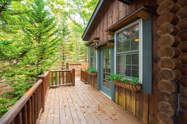 Una cabaña de madera con terraza, ventanas grandes y revestimiento de troncos.
