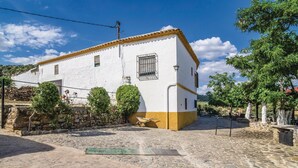Un edificio blanco con base amarilla, una ventana pequeña y un portón de metal.