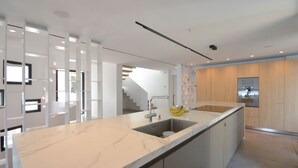 Een moderne keuken met een marmeren aanrecht, een spoelbak en een houten kast.