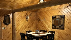 Une salle à manger avec un plafond et des murs en bois, une table ronde entourée de chaises et des décorations en forme de bois de cerf.