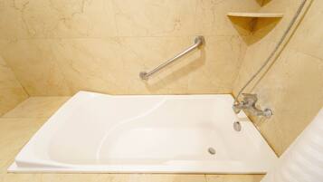 Un baño con bañera, barra de apoyo y cabezal de ducha.