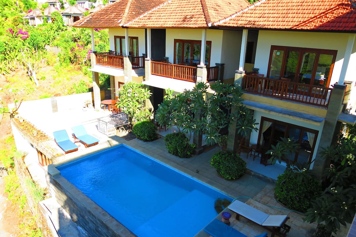 A two-story house with a swimming pool, a balcony, and a garden.