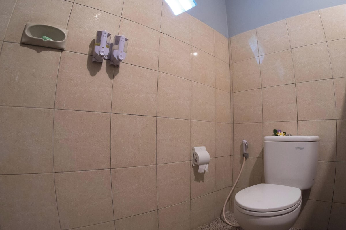 A bathroom with a toilet, a paper towel dispenser, and a soap dispenser on the wall.