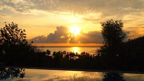 Atardecer sobre un cuerpo de agua, con siluetas de árboles y un cielo despejado.