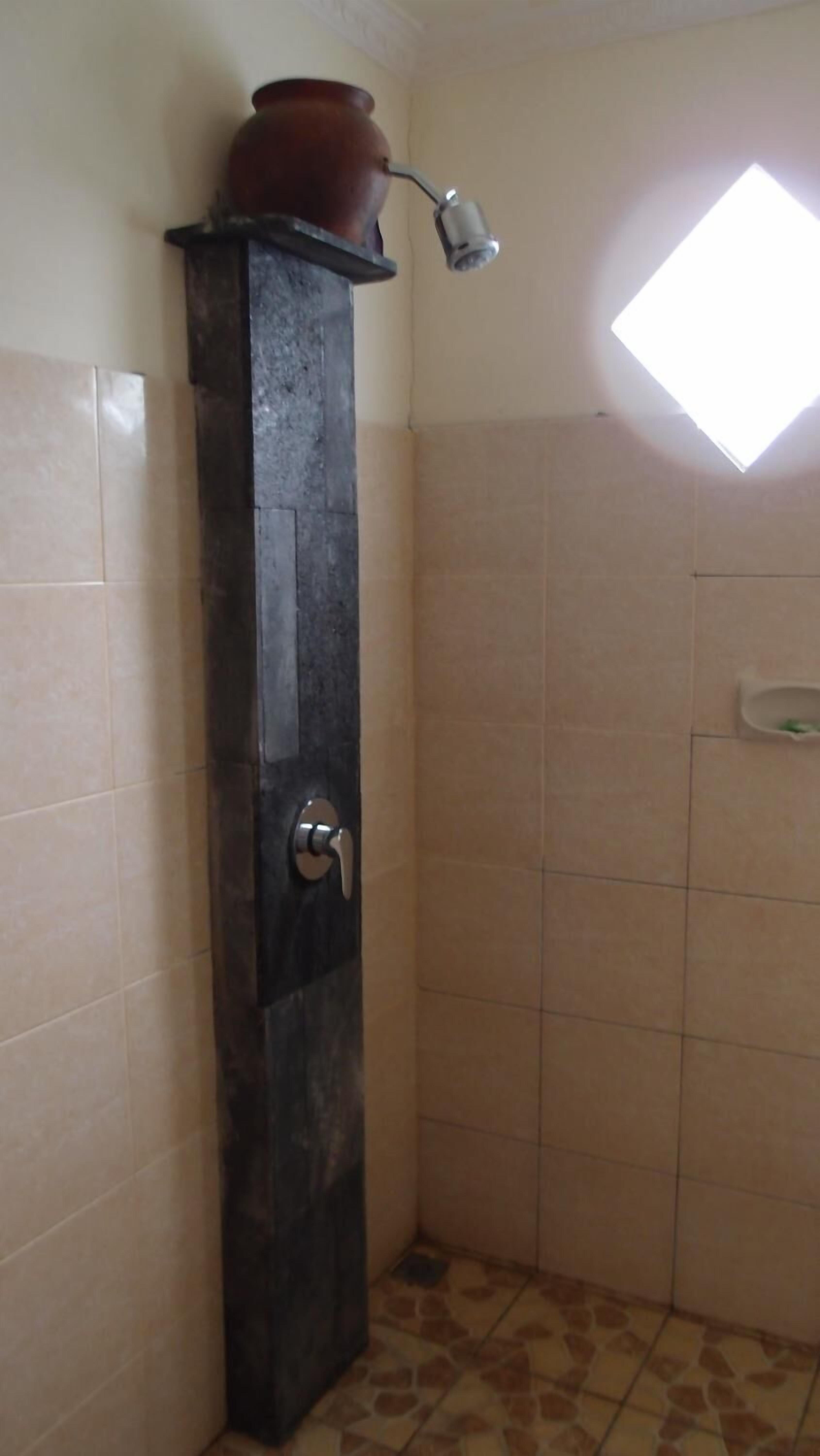 A bathroom with a shower stall, a towel rack, and a window.