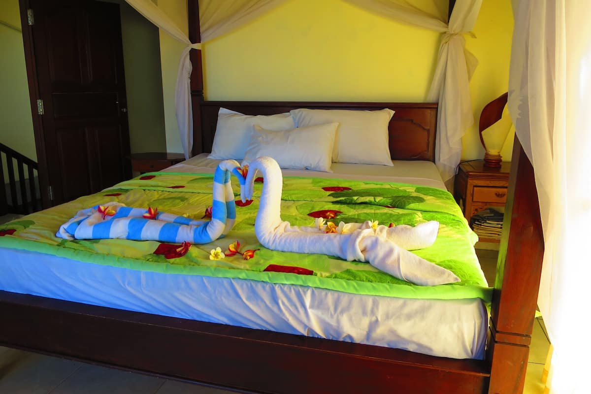 A bed with a canopy, a wooden headboard, and a bedside table with a lamp.
