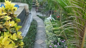 Un sendero en un jardín que lleva a una casa con techo de tejas.