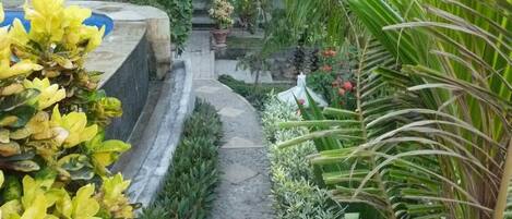 Un sendero en un jardín que lleva a una casa con techo de tejas.
