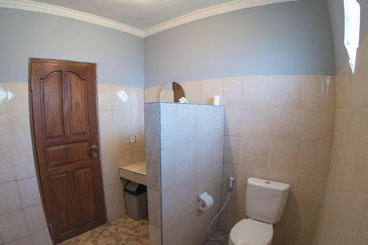 A bathroom with a wooden door, a sink, a toilet, and a shower area.