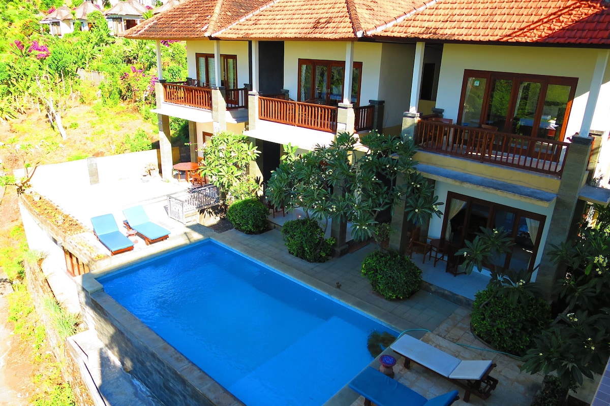 Una casa de dos pisos con piscina, mobiliario exterior y jardín.