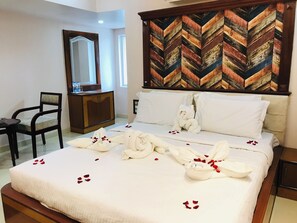 A hotel room with a bed, a wooden headboard, a mirror, a desk, and a chair.