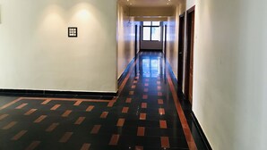 A hallway with a patterned floor, a window at the end, and a door on the right. - NAVEED RESIDENCY (Anantapur)