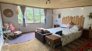 Un dormitorio con cama, una silla, un escritorio y una ventana con cortinas.