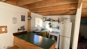 Una cocina con una isla de madera, estufa a gas, fregadero y refrigerador.