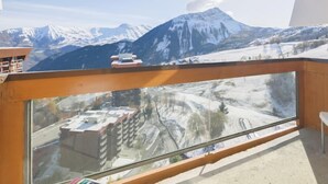A balcony with a view of snow-covered mountains and a clear sky.