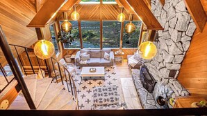 Un intérieur en bois avec un mur en pierre, une cheminée et un coin salon comprenant un canapé et une table basse.