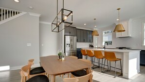 A modern kitchen with a central island, wooden chairs, pendant lighting, and stainless steel appliances. - Walk to Hip Bars* Photo wall* porch swings * designer home*  (B) (Nashville)