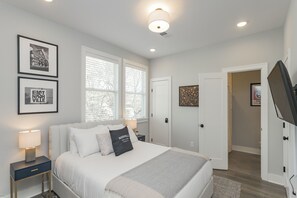 Une chambre à coucher avec un lit, des tables de chevet, une télévision et des tableaux encadrés accrochés au mur.