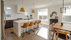 A modern kitchen with a central island, bar stools, and pendant lighting. - Walk to Hip Bars* Photo wall* porch swings * designer home*  (B) (Nashville)