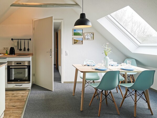 A modern kitchen with an oven, a dining area with a table set for two, and a skylight above.