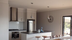 A modern kitchen with a central island, stainless steel appliances, and wooden flooring.