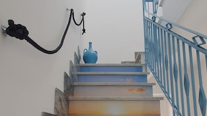 Uma escadaria com corrimão azul e um vaso no patamar.
