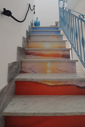 Un escalier avec une rampe bleue et une clé accrochée au mur.