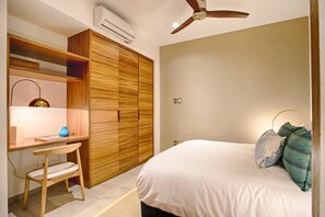 A bedroom with a bed, a desk, a wardrobe, and a ceiling fan.