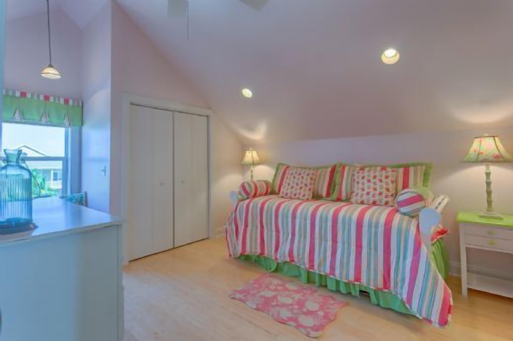 Un dormitorio con cama, lámparas de noche, una ventana con cortinas y una mesita con lámpara.