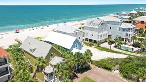 Un quartier résidentiel situé sur la côte, avec des maisons donnant sur la plage, une plage de sable et une vue dégagée sur l’océan.