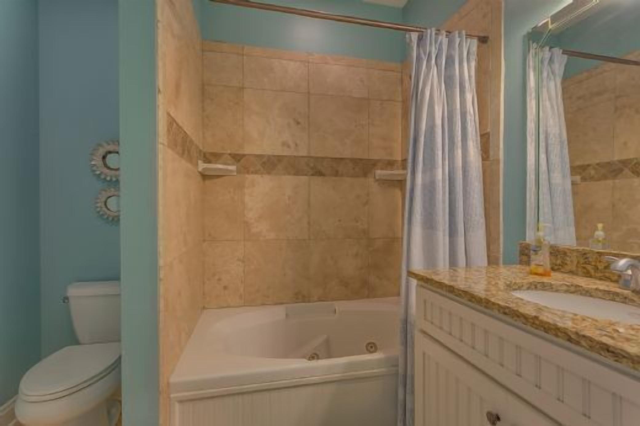 Un baño con bañera, cortina de ducha, inodoro y lavamanos con espejo.