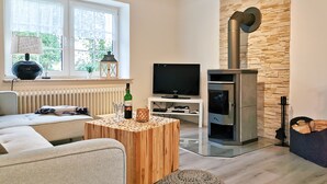 A modern living room with a stone wall, a fireplace, a television, and a cozy seating area.