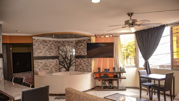 Un salon moderne doté d’un grand téléviseur, d’un ventilateur de plafond, d’un coin repas et d’une baignoire.