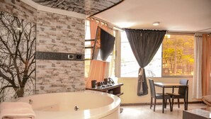 Une salle de bain avec une grande baignoire, un miroir et une fenêtre avec des rideaux.