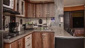 Une cuisine moderne avec des meubles en bois, un four à micro-ondes, un grille-pain et une machine à café.