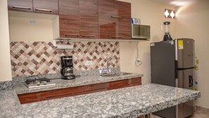 A kitchen with granite countertops, a coffee maker, a refrigerator, and wooden cabinets. - King One bedroom AC HOT TUB ELEVATOR 2 Flat screens (Medellin)