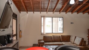 A living room with a brown leather sofa, a coffee table, and a TV on a wooden stand. - 5 Bed PH ENTIRE ROOF HOT TUB ELEVATOR Private roof Guests with Photo ID (Medellin)
