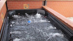A hot tub with water, surrounded by brick walls and a tiled floor. - 5 Bed PH ENTIRE ROOF HOT TUB ELEVATOR Private roof Guests with Photo ID (Medellin)