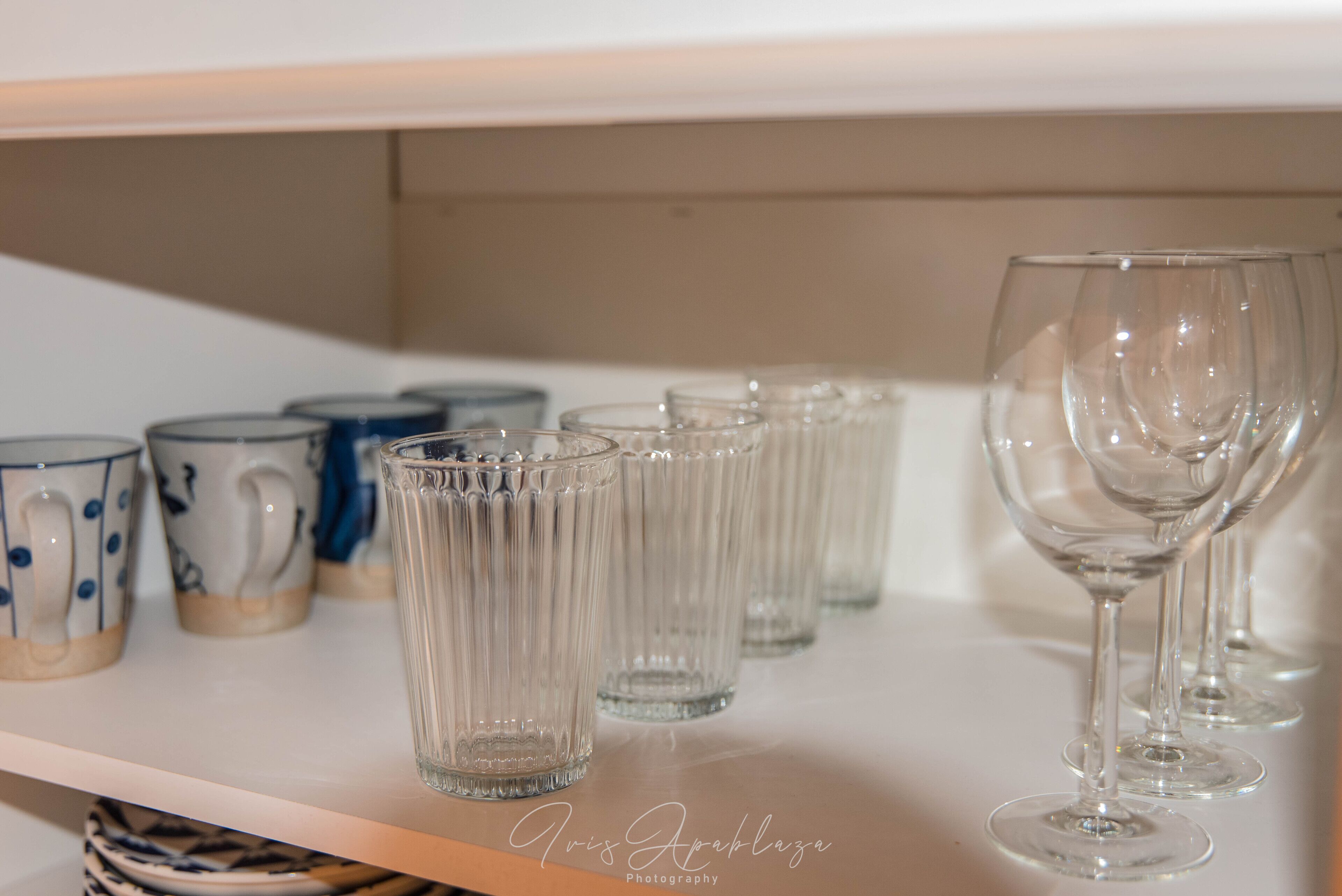 A shelf with various glassware, including clear tumblers and wine glasses.