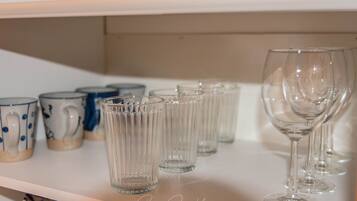 A shelf with various glassware, including clear tumblers and wine glasses.