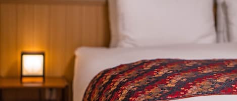 A hotel room with a bed, a nightstand, and a lamp.