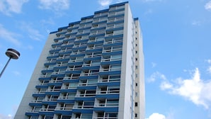 A tall, modern building with a grid of balconies and a clear blue sky in the background. - Frische Brise (Cuxhaven)